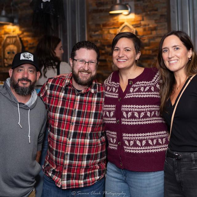 Four friends smiling at a client appreciation night